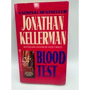 May include: A paperback book with a red cover featuring the title "BLOOD TEST" in large blue letters. The author's name, "JONATHAN KELLERMAN," is prominently displayed in white. The cover also includes the text "NATIONAL BESTSELLER" and "AN ALEX DELAWARE NOVEL."