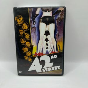 May include: A DVD case for the movie "42nd Street" featuring a vintage movie poster. The poster shows a stylized image of legs in black shorts and red shoes, with the movie title in large white letters.