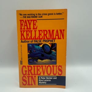 May include: A paperback book titled "Grievous Sin" by Faye Kellerman. The cover is predominantly orange with the title in large red letters. The book features a blue car on the cover and text that reads "A Peter Decker and Rina Lazarus Mystery."