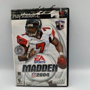 以下が含まれることがあります： PlayStation 2 用の Madden NFL 2004 ビデオゲームケース。表紙には、背番号 7 のファルコンズのユニフォームを着たフットボール選手が描かれています。EA Sports のロゴ、NFL のロゴ、ゲームのタイトルも表示されています。