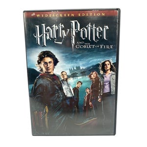 Puede incluir: Una caja de DVD de "Harry Potter y el cáliz de fuego". La portada presenta un fondo azul oscuro con el título en una fuente estilizada. Varios personajes se muestran en primer plano, con la inscripción "Widescreen Edition" en la parte superior.