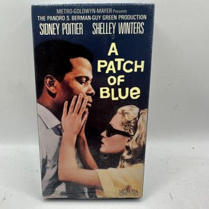 May include: A sealed VHS tape of the film A Patch of Blue, featuring Sidney Poitier and Shelley Winters. The cover art displays a dark blue background with yellow text, showing a man and a woman in sunglasses with hands touching his face.