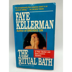 May include: A paperback book titled "The Ritual Bath" by Faye Kellerman. The cover is blue with white text, including the author's name and a quote from The San Diego Tribune. A small image shows a person with their hands covering their face.