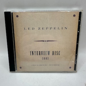 May include: A CD case featuring the text "LED ZEPPELIN" above "INTERVIEW DISC 2003". The case has a tan background with a black spine. The text "LICENSED FOR PROMOTION ONLY - SALE IS PROHIBITED" is at the bottom.