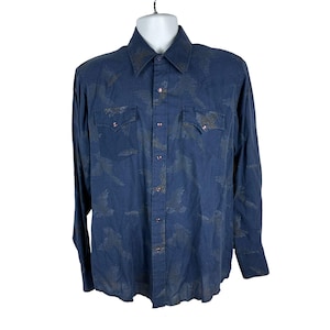 May include: A long-sleeved, navy blue button-down shirt with a subtle, repeating pattern. The shirt features two chest pockets with pointed flaps and pearl snap closures. The collar and cuffs are a darker shade of blue.