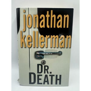 May include: A hardcover book titled "Dr. Death" by Jonathan Kellerman. The book cover features the author's name in gold lettering, with a black and white background. A silver door handle graphic is also on the cover.