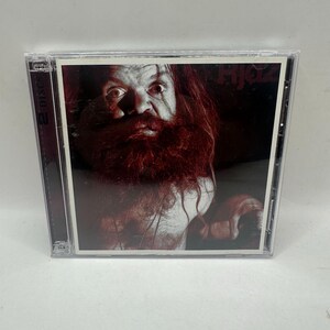 May include: A two-disc CD case featuring a dark, high-contrast cover image of a person with a long, thick, reddish-brown beard and intense eyes. The text "Hjölz" is printed in the upper right corner in a dark, stylized font against a black background.