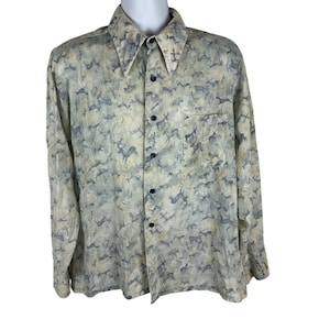 May include: A long-sleeved button-down shirt with a beige and blue deer pattern. The shirt has a classic collar, a chest pocket, and black buttons. The fabric has a slightly textured appearance.