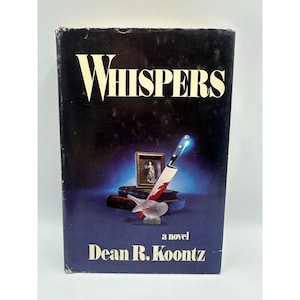 May include: A vintage hardcover book titled "Whispers" by Dean R. Koontz. The cover features a knife with blood, a small framed picture, and a glass bird. The book has a dark blue background with white lettering.