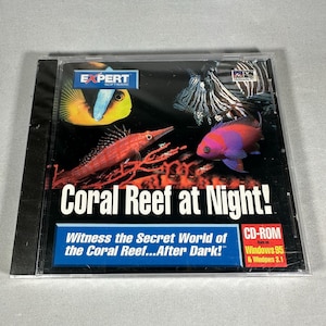 Puede incluir: Una caja de CD-ROM con el título "Coral Reef at Night!" y ilustraciones de peces y corales coloridos. La portada incluye el logotipo de Expert Software y el texto: "Witness the Secret World of the Coral Reef...After Dark!"