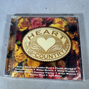 May include: A CD case with the title "Heart Full of Country" in gold lettering, featuring a heart design. The background is a collage of yellow and red roses. The CD case lists country music artists.