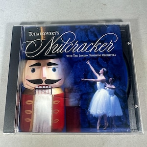 Puede incluir: Una caja de CD que presenta "El Cascanueces" de Tchaikovsky con la Orquesta Sinfónica de Londres. La portada incluye una figura de cascanueces, una bailarina y un fondo azul oscuro. La caja del CD está en una funda de plástico transparente.