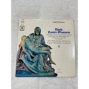 May include: A vintage vinyl record album titled "Bach: Easter Oratorio." The album cover features a sculpture of the Pieta by Michelangelo. The album is by The Philadelphia Orchestra, Eugene Ormandy, Conductor.
