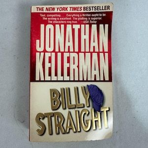 Puede incluir: Un libro de bolsillo titulado "Billy Straight" de Jonathan Kellerman. La portada presenta el nombre del autor en letras blancas grandes sobre un fondo rojo. El título está en letras doradas, con un dibujo de sombrero azul.