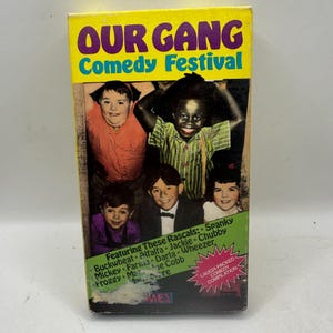 May include: A vintage VHS tape for "Our Gang Comedy Festival" with a yellow top and a picture of the cast. The tape features the names of the cast members and a "Laugh-Packed Comedy Compilation" label.