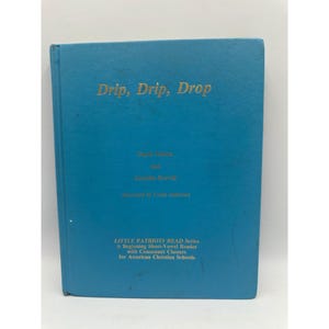 May include: A teal book with the title "Drip, Drip, Drop" in gold lettering. The book is part of the "LITTLE PATRIOTS READ Series", a short-vowel reader for American Christian Schools.