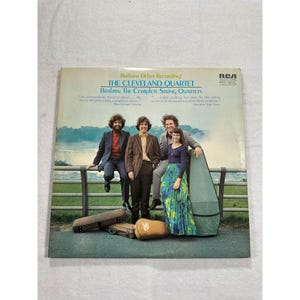 May include: Album cover for "Brahms: The Complete String Quartets" by The Cleveland Quartet. The cover features a photo of the quartet standing near a fence. The album is a "Brilliant Debut Recording" on the RCA Red Seal label.