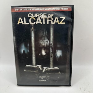 May include: A DVD case for the movie "Curse of Alcatraz." The cover features a dark, ominous design with the title in large, white letters. The image includes a ghostly figure behind prison bars, with the text "Welcome to Death Row."