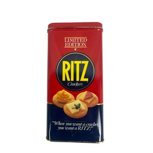 Puede incluir: Una lata rectangular roja de "Edición Limitada" de Ritz Crackers. La lata presenta el logotipo de Ritz en un círculo amarillo e imágenes de galletas saladas con aderezos. El texto "When you want a cracker you want a RITZ!" está impreso.