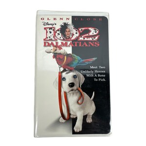 May include: A VHS tape for the Disney movie "102 Dalmatians" featuring Glenn Close. The cover shows a Dalmatian puppy with a red leash in its mouth, a colorful parrot, and the film's title.