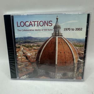 May include: A CD case with the title "LOCATIONS" in pink and the subtitle "The Collaborative Works of Bill Kohn" over an image of a cathedral dome. The years "1970 to 2002" are printed on the right side of the case.