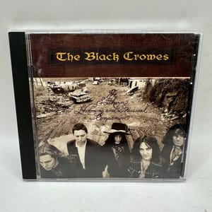 May include: CD case for The Black Crowes album, "The Southern Harmony and Musical Companion." The cover features a sepia-toned photo of the band members and a rural scene. The album title and band name are displayed in elegant fonts.