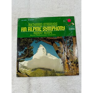 May include: A vintage vinyl record album titled "An Alpine Symphony" by Richard Strauss, featuring Rudolf Kempe and the Royal Philharmonic Orchestra. The album cover displays a scenic mountain landscape with a green and white color scheme.