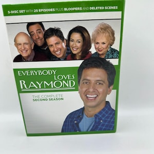 Puede incluir: Un set de caja de DVD de la serie de televisión "Everybody Loves Raymond: The Complete Second Season". La caja es verde y blanca, con imágenes del elenco. El texto en la caja incluye "5-DISC SET" y "25 EPISODES PLUS BLOOPERS AND DELETED SCENES."