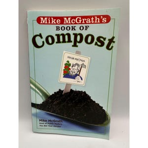 May include: A book titled "Mike McGrath's Book of Compost" with a light blue cover. The cover features the title in large, dark brown letters and a drawing of a sign with a man and gardening tools. The book is about composting.