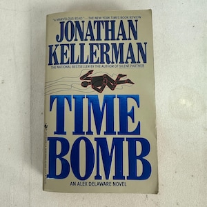 May include: A paperback book titled "TIME BOMB" by Jonathan Kellerman. The cover features the title in large, blue, block letters. The author's name is in a larger font above the title. A black and red graphic of a person is above the title.
