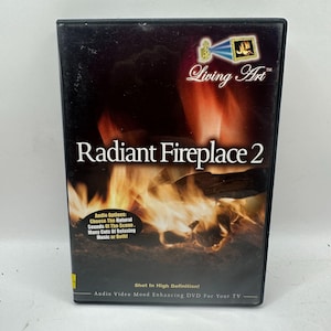 May include: A black DVD case with the title "Radiant Fireplace 2" in white letters. The cover features a vibrant image of a fireplace with orange and yellow flames. The DVD is labeled "Living Art" and includes text about audio options and high definition.