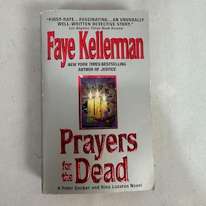 May include: A paperback book titled "Prayers for the Dead" by Faye Kellerman. The cover features red text on a light gray background, with an image of candles. The book is a Peter Decker and Rina Lazarus novel.
