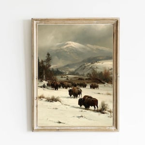 May include: A framed landscape painting depicting a herd of dark brown bison walking across a vast, snow-covered valley. In the background, a large, snow-capped mountain rises under a cloudy, overcast sky, with sparse trees dotting the terrain.