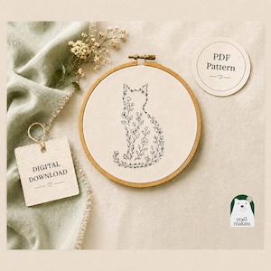 Puede incluir: Un bastidor de bordado circular de madera que contiene un panel de tela blanca con una ilustración de línea negra de una silueta de gato llena de motivos florales. Una etiqueta cuadrada dice DIGITAL DOWNLOAD y una redonda PDF Pattern.