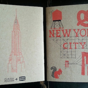 May include: A red and black illustration of the New York City skyline, including the Empire State Building, a water tower, a pretzel, and a bridge. The text "NEW YORK CITY" is printed in red letters. The illustration is on a brown background.