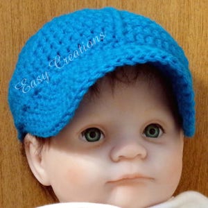 Puede incluir: Un beb&eacute; con un gorro de punto azul brillante con visera. El gorro tiene el texto "Easy Creations" bordado en un lateral.