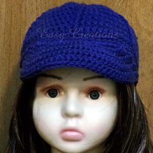 Puede incluir: Un gorro azul tejido a crochet con visera. El gorro tiene un dise&ntilde;o texturizado y las palabras "Easy Creations" est&aacute;n bordadas en la parte delantera.