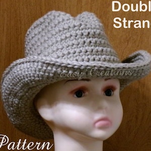 Peut inclure: Un chapeau de cowboy en crochet gris avec un large bord. Le chapeau est réalisé avec un fil double et présente un design simple et classique. Le texte "Double Strand Pattern" est visible sur l'image.