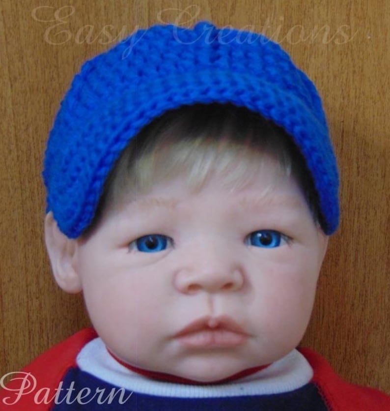 Puede incluir: Una gorra de b&eacute;isbol de crochet azul con visera. La gorra la lleva un beb&eacute; con el pelo rubio y los ojos azules.
