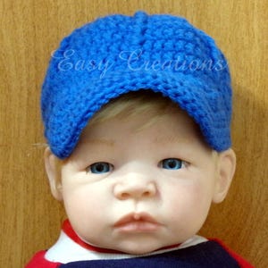 Puede incluir: Un beb&eacute; con una gorra de b&eacute;isbol de crochet azul. La gorra tiene visera y est&aacute; hecha con un punto texturizado.