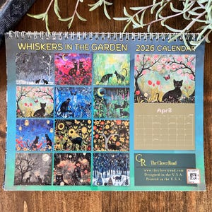 May include: A spiral-bound 2026 calendar titled "Whiskers in the Garden." The calendar features monthly illustrations of black cats in various garden settings. The April page is visible, with a black cat under a flowering tree. The Clover Road logo is at the bottom.