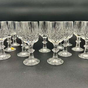 May include: A collection of clear crystal wine glasses. Each glass features a textured, vertical pattern on the bowl, a decorative stem, and a round base. The glasses are arranged on a dark surface.