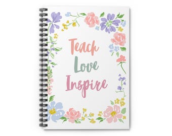 May include: Spiral-bound notebook with the words "Teach Love Inspire" in pastel colors. The notebook is surrounded by a floral wreath of pink, purple, blue, and yellow flowers and green leaves. The notebook has a white background.