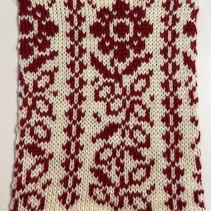 May include: A rectangular knitted fabric swatch featuring a two-tone color scheme of deep red and off-white. The pattern displays vertical columns of stylized floral motifs and geometric leaf designs created using a stranded knitting technique.