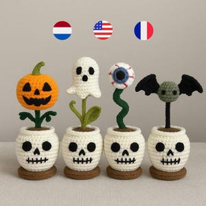 Puede incluir: Decoraciones de Halloween hechas a ganchillo, con una calabaza, un fantasma, un ojo y un murciélago, cada uno sobre una maceta con forma de calavera. Los colores son blanco, naranja, verde y negro, con bases marrones. Ideal para Halloween.