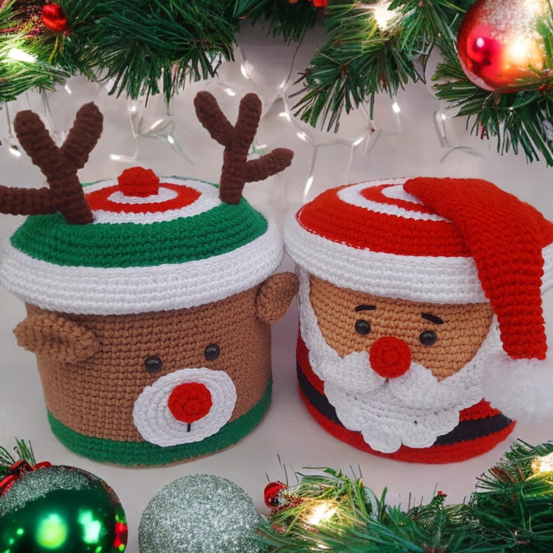 May include: Two crocheted Christmas-themed tissue box covers. One is a reindeer with brown antlers, a red nose, and a green and white striped hat. The other is Santa Claus with a white beard, a red hat, and a red and white striped hat.