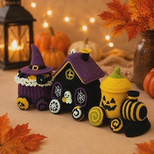 Puede incluir: Un set de tren de Halloween tejido a ganchillo con tres vagones conectados. El primero es un vagón con forma de sombrero de bruja morado, el segundo una casa negra con un fantasma y ventanas de telaraña, y el tercero una locomotora calabaza amarilla.