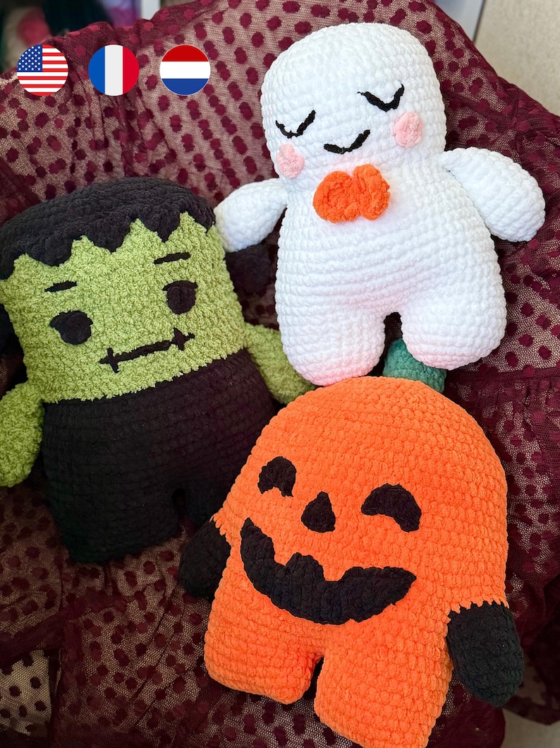 May include: Three plush crochet toys featuring a green monster with black hair, a white ghost with pink cheeks and an orange bow, and an orange pumpkin with a black face. Each figure is crafted from soft yarn with embroidered facial details.