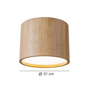 May include: A cylindrical lampshade with a light wood grain finish. The lampshade has a diameter of 31 cm (12.2 inches). The interior of the lampshade is illuminated with a warm, soft light.