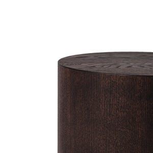 May include: A dark brown, cylindrical wooden side table. The table has a smooth, rounded top and a textured, vertical grain pattern. The wood has a rich, warm tone, and the design is simple and modern.